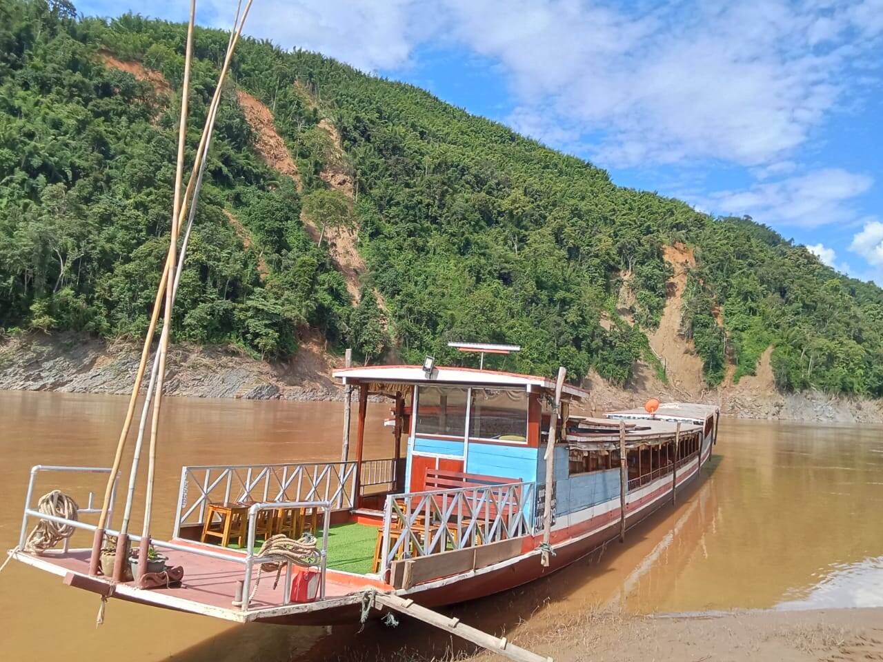 Slow boat moored against a forested bank, gangway down